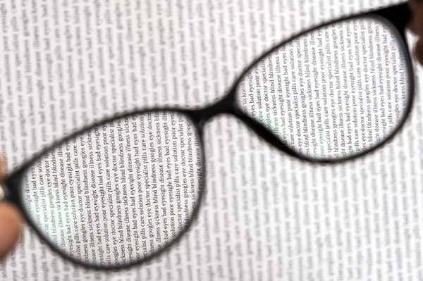 Unfocused black eyeglasses with view of sharp text through lenses. Bad eyesight concept. Eyecare concept. Reading concept. Health care concept.